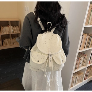 Detail view of white star print faux leather backpack with buckle closure and side drawstrings