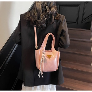 Sac à main rose brillant avec logo triangle doré et breloque sur costume noir