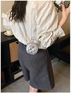 Mini sac rond argenté matelassé avec fleur en métal, porté par un mannequin en mode lifestyle