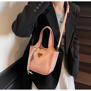 Sac fourre-tout rose en similicuir avec plaque triangulaire dorée porté en mode street style