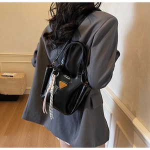 Vue détaillée d'un sac à main en cuir verni noir avec décor triangle jaune