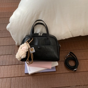 Detail of black Boston bag with double zippers, pocket and plush sheep charm