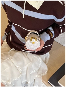 Détail d'un mini sac rond blanc matelassé avec fermeture éclair fleurie dorée et chaîne