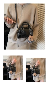 Detail of black patent leather handbag with detachable shoulder strap and puppy pendant
