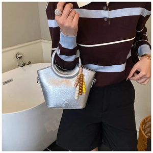 Silver mini bucket bag with crackle texture and colorful bead charm shown on model