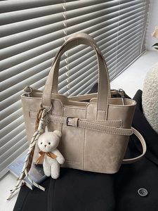 Minimalist beige bucket bag with retro faux leather texture and plush bear charm