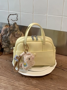 Yellow Boston handbag for women with plush alpaca charm on a wooden tabletop