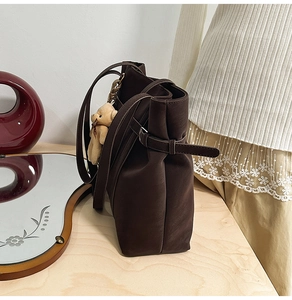 Detail view of dark brown PU leather tote with side buckles and cute bear charm