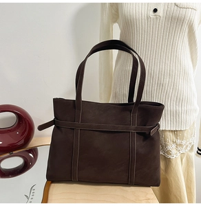 Detail of dark brown tote bag showing smooth matte texture and stylish side strap detail