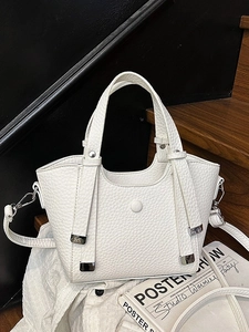 Sac seau blanc chic en cuir grainé avec détails argentés sur un fond en bois chaud