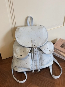 Light blue canvas star pattern backpack with drawstring and metal buckles in a cozy room