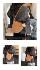 Detail einer braunen Satteltasche aus Leder mit weißen Nähten und Bärenanhänger