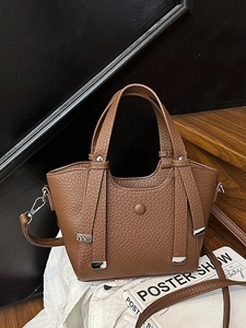 Sac seau en cuir marron avec détails argentés sur fond de tissu blanc plissé