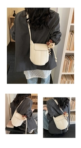 Detail der cremefarbenen Leder-Beuteltasche mit Plüschbären-Anhänger und Schleifen-Deko