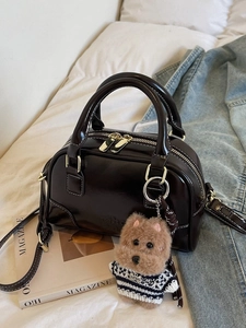 Dark brown shell bag with white contrast stitching and a cute puppy plush charm