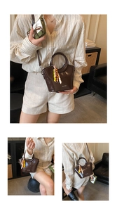 Deep brown patent leather bucket bag with colorful bead charm and crossbody strap view