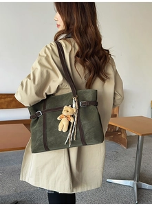 Retro dark green tote bag with bear charm and decorative silk scarf worn over a beige coat