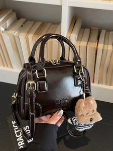 Brown leather shell bag with handle, shoulder strap and a cute puppy plush charm