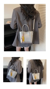 Detailansicht einer silbernen Eimertasche mit Perlenanhänger und strukturierter Oberfläche