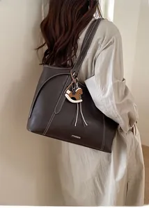 Detail of coffee brown leather tote bag with white stitching and wooden horse charm
