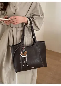 Detail of dark brown leather tote bag with white contrast stitching and horse charm
