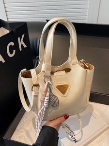 Grand sac bandoulière crème avec texture cuir et breloque tennis pour le quotidien