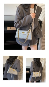 Detail of silver metallic shoulder bag with gold chain strap and square metal buckle