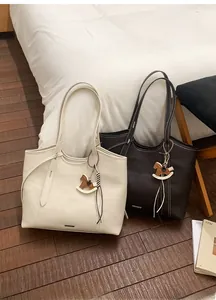 Detail of minimalist leather tote bags with trojan horse charms and metal logo details