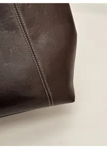 Macro shot of dark brown leather tote showing fine white contrast stitching and texture