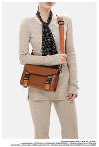 Detailed view of caramel brown messenger bag with adjustable strap and plastic buckle
