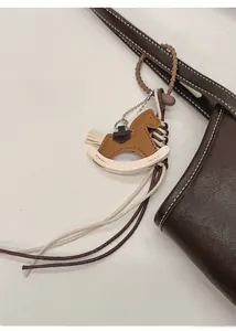 Detail of a brown and white leather rocking horse charm attached to a leather tote bag