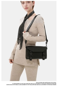 Detail of adjustable litchi texture strap and buckle on black leather crossbody bag