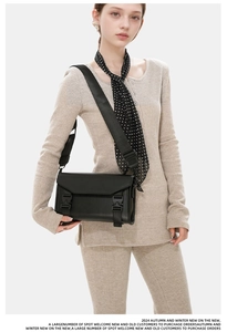 Detailed view of the tactical buckle and leather texture on a black crossbody bag