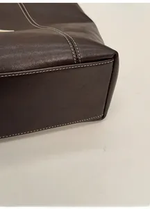 Detail of double-stitched corners and pebble grain leather on brown tote bag bottom