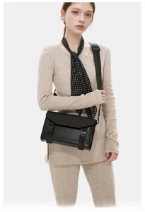 Detail of black crossbody messenger bag featuring industrial quick-release buckles