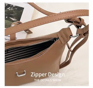 Detail view of the silver metal zipper and black-white striped lining on the brown bag
