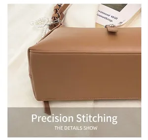 Detail of precise stitching on caramel leather handbag base with pearl charm accent