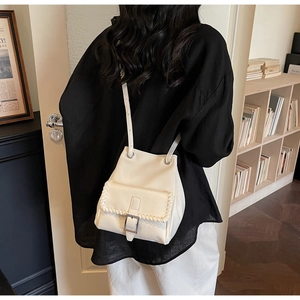 Détail d'un sac seau blanc crème avec bordure tressée et boucle en métal doré