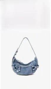 Vue de face d'un sac demi-lune en denim rétro avec fermetures éclair en métal