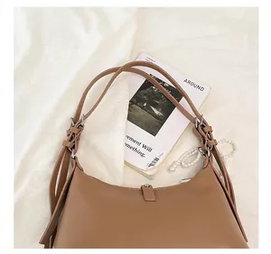 Detail of adjustable strap with metal buckle on caramel leather shoulder bag