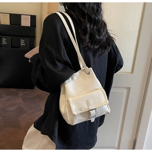 Détail du sac seau en cuir blanc avec bords tressés et fermoir métallique à l'épaule