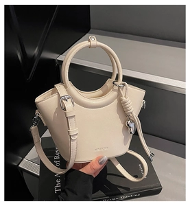 Détail du sac seau crème avec poignée ronde, breloque cœur et bandoulière réglable