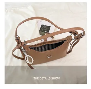 Detail view of brown dumpling bag featuring striped lining and elegant pearl charm