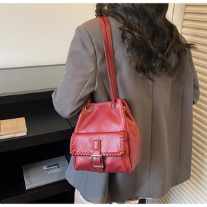 Détail du sac seau rouge montrant la couture tressée et la boucle en métal vintage