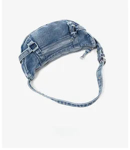 Détail du sac demi-lune en denim bleu montrant la texture délavée et les boucles cargo