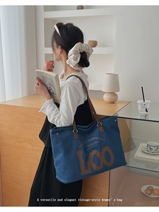 Détail du sac cabas en denim bleu foncé avec anses en cuir marron et lettrage vintage
