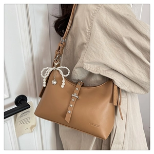 Detail of caramel faux leather shoulder bag with metal studs and pearl heart charm