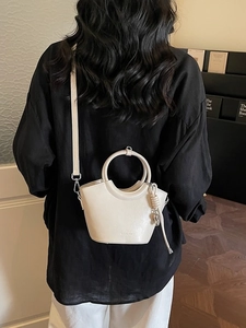 Sac seau minimaliste beige avec poignée ronde et bandoulière dans une scène lifestyle