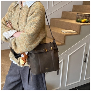 Detail der dunkelbraunen Beuteltasche mit Goldschnalle und Bären-Anhänger