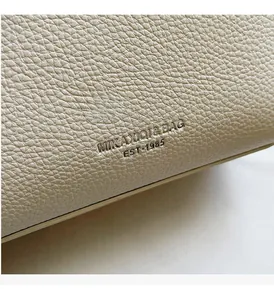 Close-up of litchi grain leather texture with MIKAXIQI & BAG embossed logo detail
